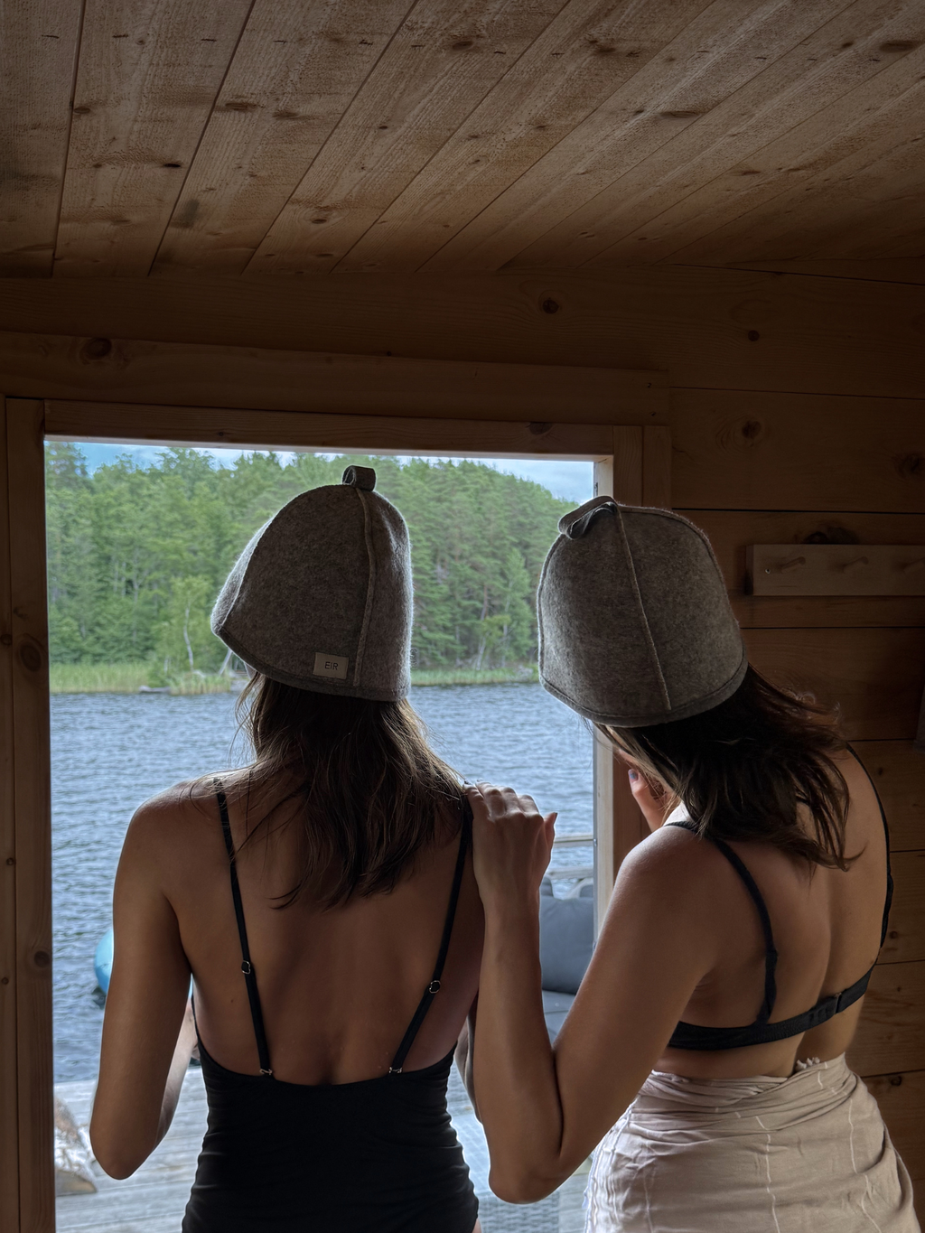 Two girls wearing the EIR studio saunahats in 100% virgin wool in the colour light grey for heat protection
